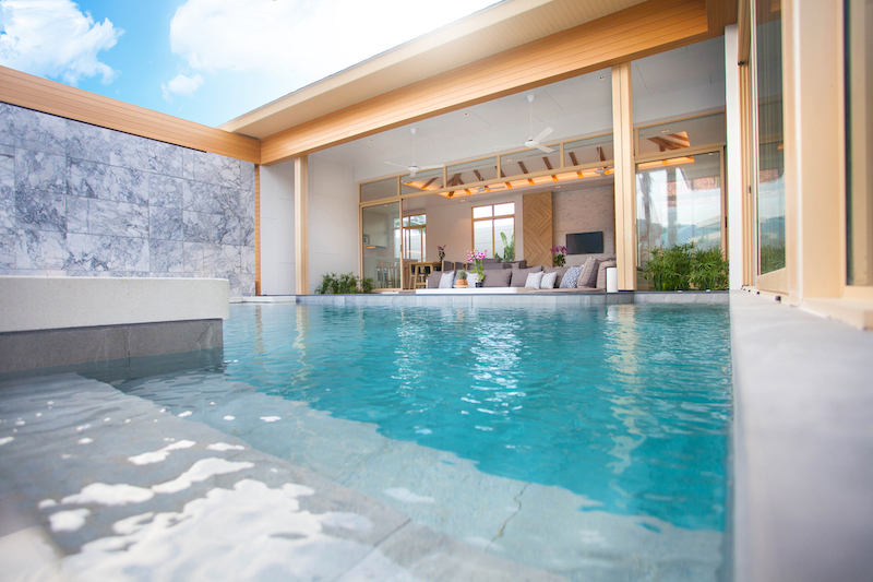 Luxury exterior design in living room of pool villas. Airy and bright space with high raised ceiling and wooden dining table
