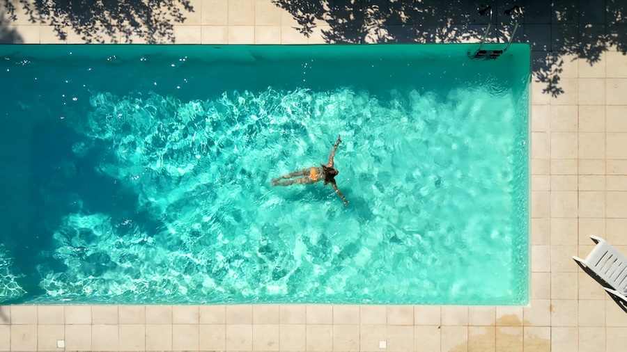Woman Swimming in Her Pool from Direct Top-Down Aerial View