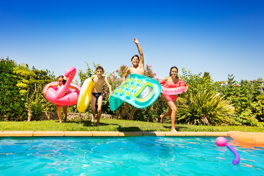 Portrait of happy teenagers with swimming tools, running and jumping into the water