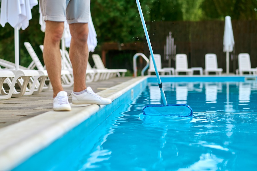A service person cleaning the swimming pool